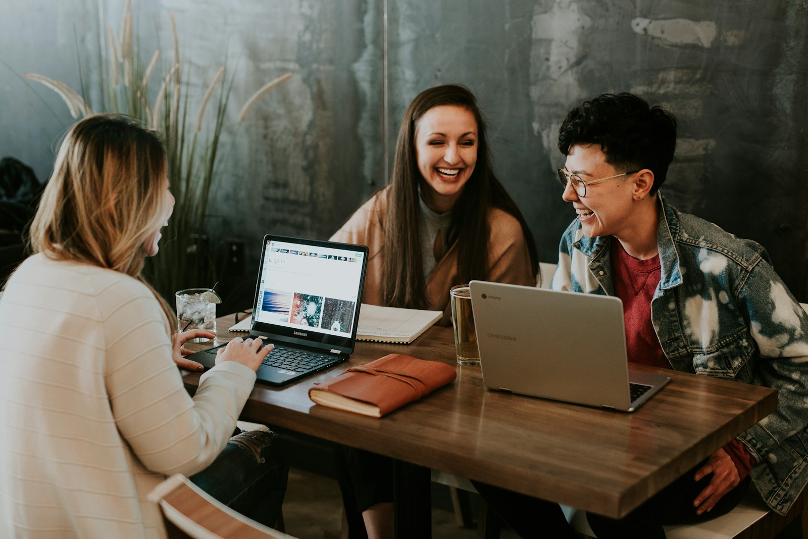 Three people collaborating happily around their laptops